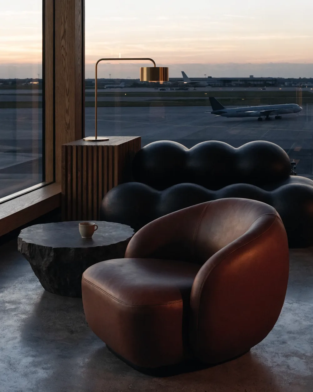 A quiet airport lounge with warm light and views across the airfield.